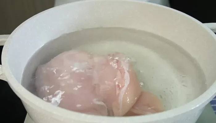 Cocer el pollo con agua caliente y sal hasta que esté suave (75.0). Desmenuzarlo con dos tenedores (98.759).