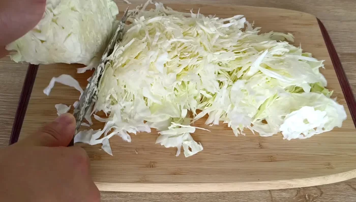 Preparamos el repollo: Enjuagamos bien un repollo blanco pequeño bajo agua fría. Lo cortamos por la mitad, retiramos la parte central dura y cortamos el repollo en tiras finas.