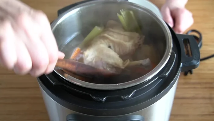 Sacar el pollo de la olla a presión. Colar los garbanzos y reservar el caldo.
