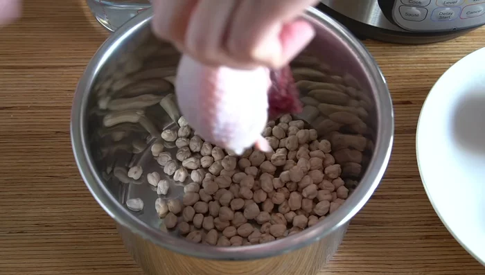 Cocer los garbanzos a presión junto con un muslo de pollo, apio, zanahoria y pimienta negra en 1200 ml de agua durante 40 minutos.