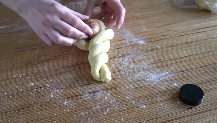 Colocar un huevo encima de la masa para formar la mona de pascua. Redondear la masa y darle tensión.