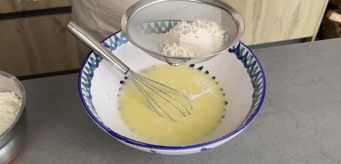 Incorporar la harina a la mezcla de huevos, tamizándola en dos o tres tandas y mezclando bien hasta que las varillas no puedan con la masa.