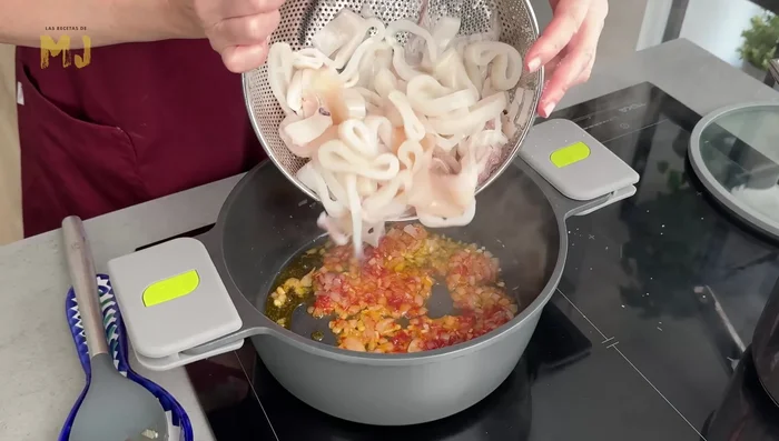 Salar los calamares y añadirlos a la cacerola. Remover y verter 100 ml de vino tinto.