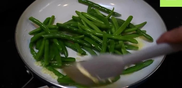 Agrega los ejotes, sal y pimienta. Agrega dos cucharadas de agua, tapa y cocina por 3 minutos a fuego medio (330.68).