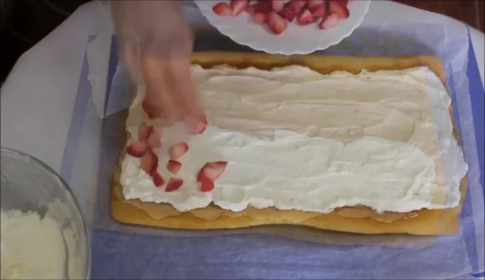 Rellenar el bizcocho con la mitad de la nata. Cubrir con fresas troceadas y enrollar con cuidado. Refrigerar durante 2-3 horas.