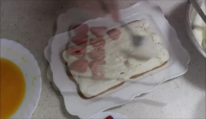 En una bandeja, poner capas de bizcochos remojados, crema de queso y nata, fresas laminadas, repitiendo las capas. Decorar con la crema restante y fresas. Refrigerar.