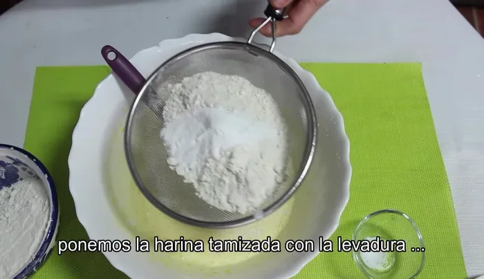 Añadir la harina tamizada con la levadura poco a poco, mezclando y amasando hasta obtener una masa uniforme que se pegue ligeramente a las manos.