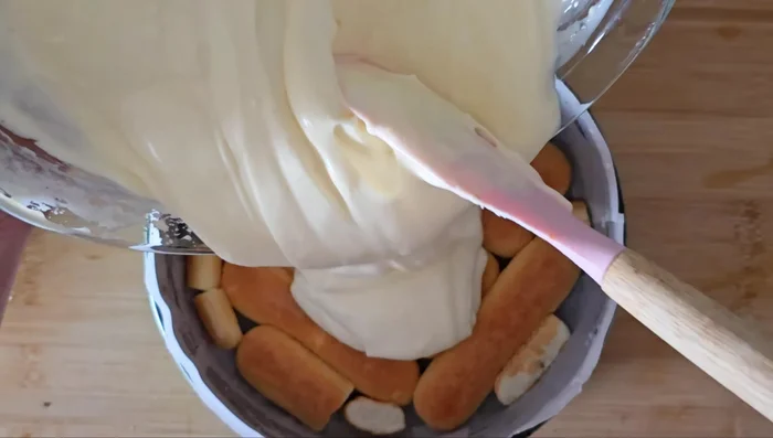 Verter la crema sobre los bizcochos en el molde.