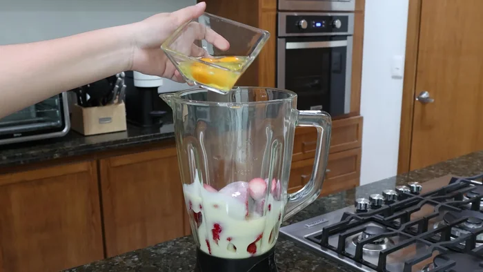 Añadir media taza de leche condensada, dos huevos, un chorrito de esencia de vainilla y una barra de queso crema a la licuadora. (41.76)