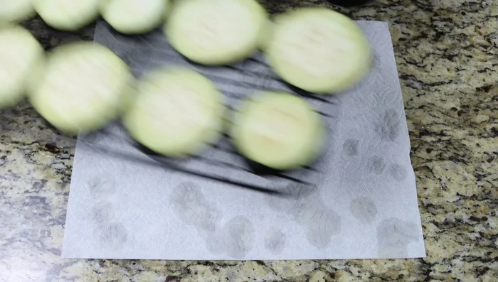 Después de 15 minutos, secar las rodajas de berenjena con toallas de papel, quitando el exceso de sal si es necesario.