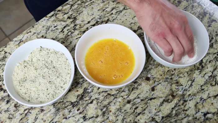 Rebozar las rodajas de berenjena: pasar por harina, luego por huevo batido y finalmente por el pan rallado. Asegurarse de que estén completamente cubiertas.
