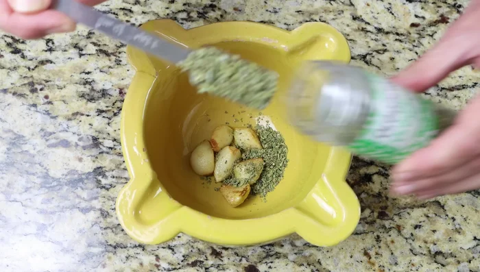 Mientras las patatas se fríen, agregar al mortero con el ajo frito: orégano, pimentón, azafrán, perejil y sal (148.64). Machacar hasta conseguir una textura tipo pasta (181.92). Si no tienes mortero, puedes usar un procesador de alimentos (189.12).