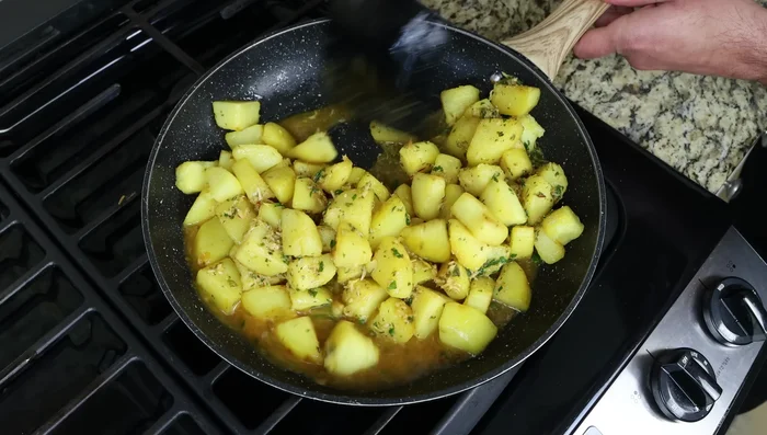 Cocinar a fuego lento durante 3-4 minutos (276.479) hasta que las patatas hayan absorbido el líquido de la salsa.
