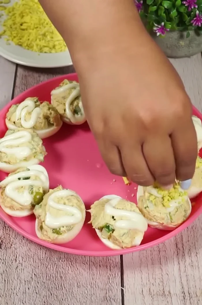 Rallar una yema cocida por encima de los huevos rellenos para decorar.