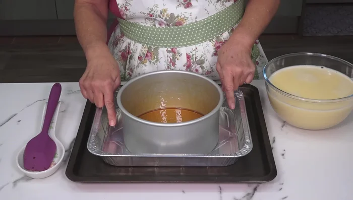 Colocamos el molde con caramelo dentro de otro molde más grande (para el baño María). Vertemos la mezcla del flan en el molde, ayudándonos de una cuchara.