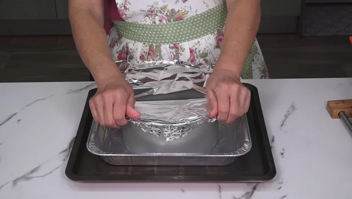 Tapamos el molde con papel aluminio y lo colocamos en el molde más grande, añadiendo agua hirviendo hasta cubrir aproximadamente 2cm del borde del molde.