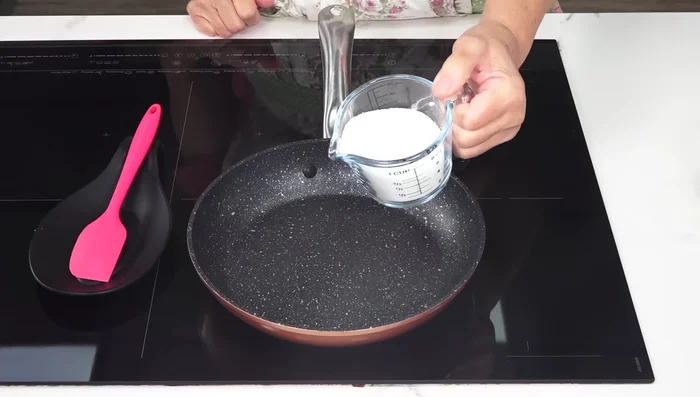 Preparamos el caramelo: En una sartén a fuego medio, añadimos el azúcar y el zumo de limón. Removemos suavemente hasta que el azúcar se derrita y adquiera un color ámbar. Añadimos el agua caliente y cocinamos durante 3 minutos, removiendo con una espátula.