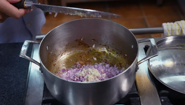 En la cacerola, sofreír la cebolla y el ajo hasta caramelizar (6-7 minutos). Agregar pimienta y sal.
