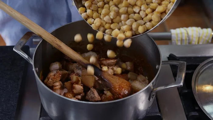 Agregar la panceta dorada, los garbanzos, caldo de pollo, agua, tomillo y laurel a la cacerola. Cocinar tapado durante 35-40 minutos.