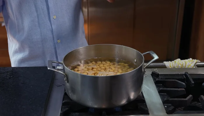 Hervir los garbanzos dos veces, desechando el agua de la primera cocción para evitar que queden pesados.