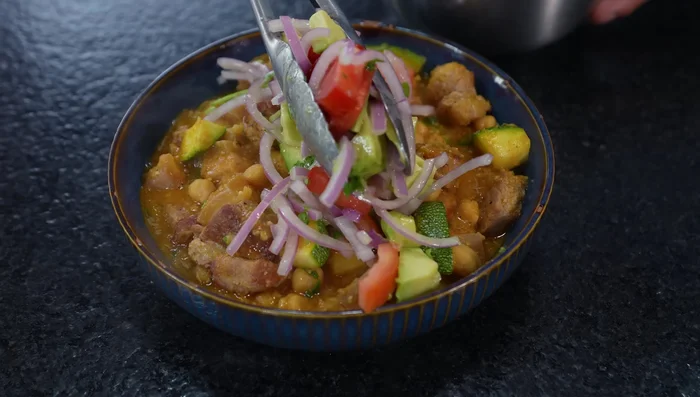 Servir el guiso de garbanzos con panceta acompañado de la ensalada.