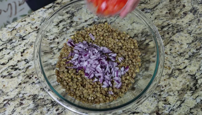 En un bol grande, mezclar las lentejas con la cebolla roja picada, el pimiento rojo picado, el pepino inglés picado y el perejil picado. Sazonar con sal y pimienta.