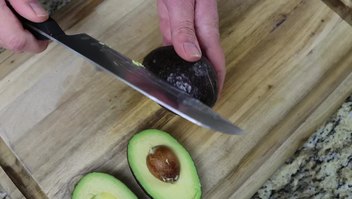Cortar los aguacates por la mitad, retirar el hueso y con una cuchara retirar un poco de pulpa para hacer espacio para la ensalada.