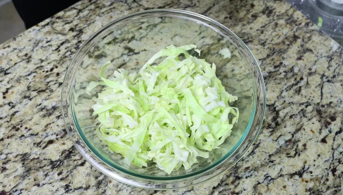 Colocar el repollo en un bol grande y sazonar con sal marina para extraer el agua y eliminar el sabor crudo.
