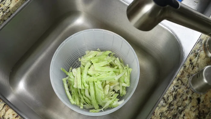 Enjuagar el repollo cortado en rodajas con agua y secarlo completamente con una centrifugadora de ensaladas o un paño de cocina.