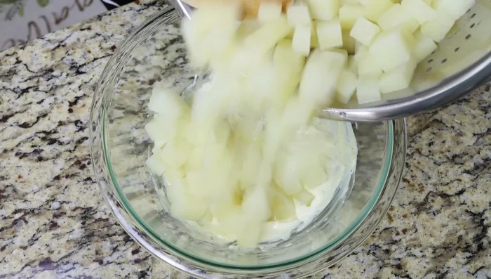Agregar las patatas a la mayonesa de ajo y mezclar suavemente.
