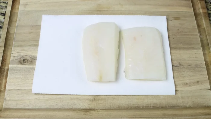 Secar los filetes de bacalao con toallas de papel y sazonar con sal y pimienta.