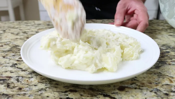 Montar el plato: colocar las patatas cremosas en un plato, encima un filete de bacalao, pimientos morrones, cebollino picado y cebollino entero como decoración.