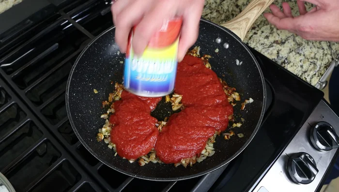 Incorpora una lata de 15oz (425g) de salsa de tomate. Sazona con sal, pimienta negra y una pizca de azúcar (opcional) si la salsa está demasiado ácida. Mezcla bien y cocina a fuego medio-bajo durante 5-10 minutos.