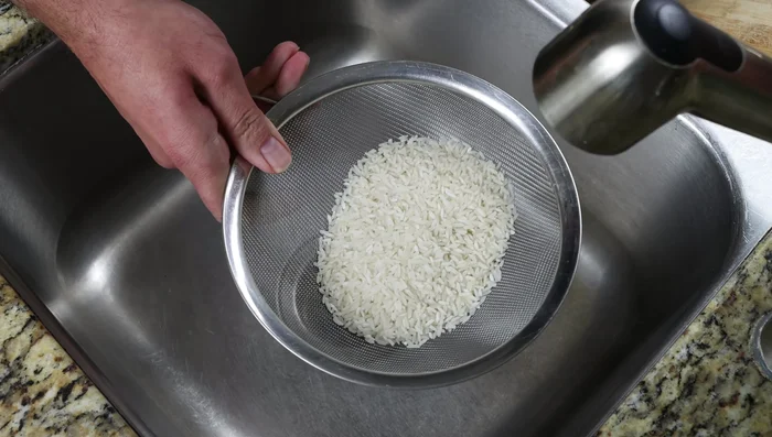 Enjuaga 1 taza de arroz de grano largo (190g) bajo el agua durante 1-2 minutos hasta que el agua salga transparente.