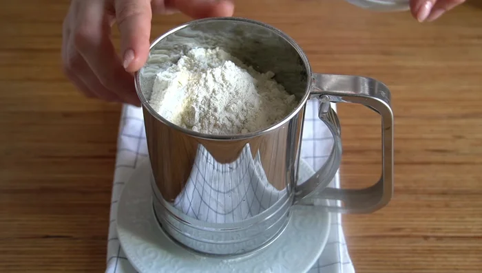 En un tamiz, mezclamos 230 g de harina y 10 g de polvos de hornear.