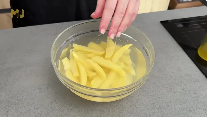Cortar las patatas, dejarlas en agua fría 15 minutos, escurrir, salpimentar y añadir aceite.