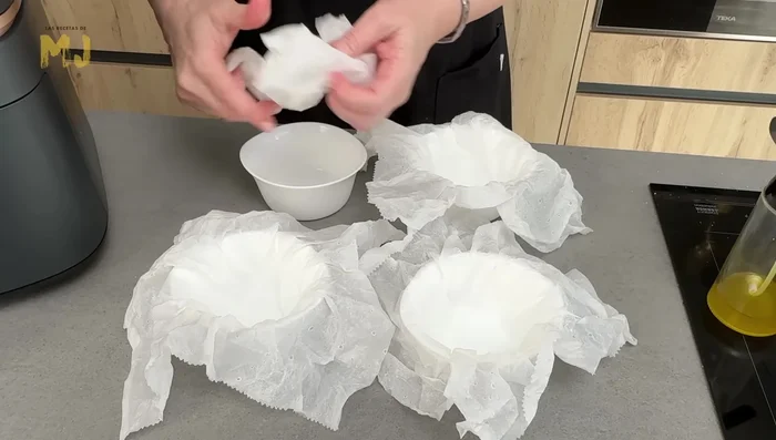 Preparar las tartas de queso: mojar papel de cocina y colocar en moldes individuales.