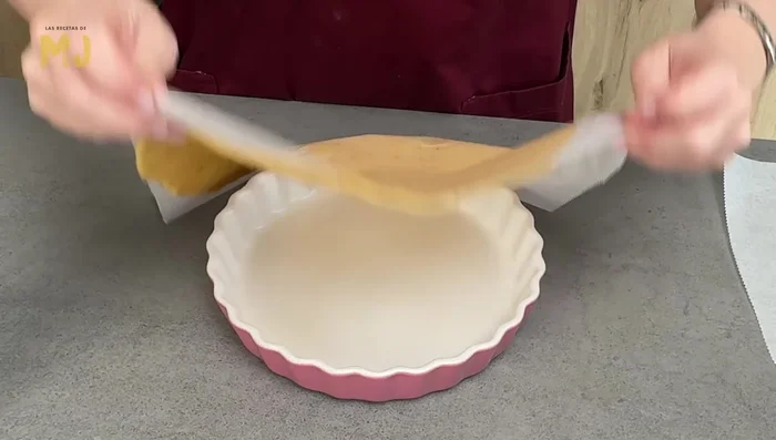 Engrasar un molde bajo de 20 cm con spray desmoldante. Colocar la masa estirada en el molde, cortar el exceso y añadir el relleno.