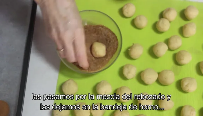 Pasamos las bolitas por la mezcla del rebozado y las colocamos en una bandeja de horno cubierta con papel de hornear.