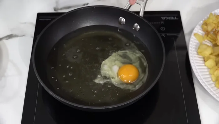 Freír los huevos en otra sartén con aceite caliente, hasta que la clara esté cuajada. Retirar y colocarlos sobre las patatas fritas.
