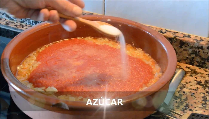 Añadir el tomate triturado, sal, azúcar (al gusto) y laurel. Integrar bien y cocer unos 15 minutos. (100.119)