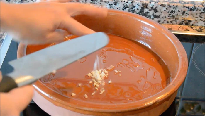 En una cazuela de barro, con un hilo de aceite de oliva, sofreír el ajo hasta que dore. Agregar la cebolla con una pizca de sal y remover. (65.239)