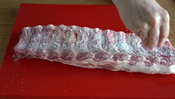 Sazonar el costillar al gusto con sal, pimentón de la Vera, ajo en polvo, pimienta negra y humo líquido. (52.28)