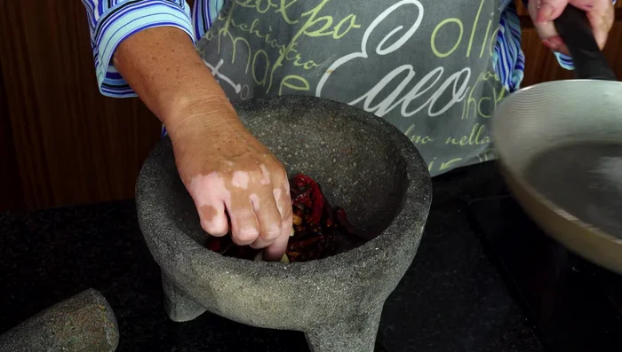 Moler en un molcajete los chiles tostados y los dientes de ajo con un poco de sal.
