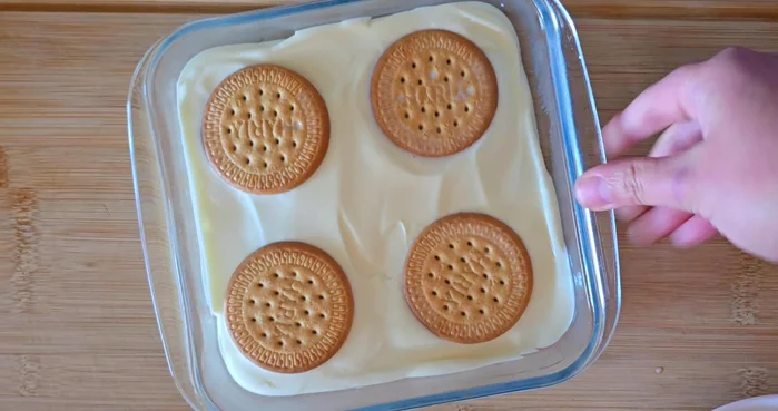 Añadir una capa de galletas empapadas en leche sobre la nata.