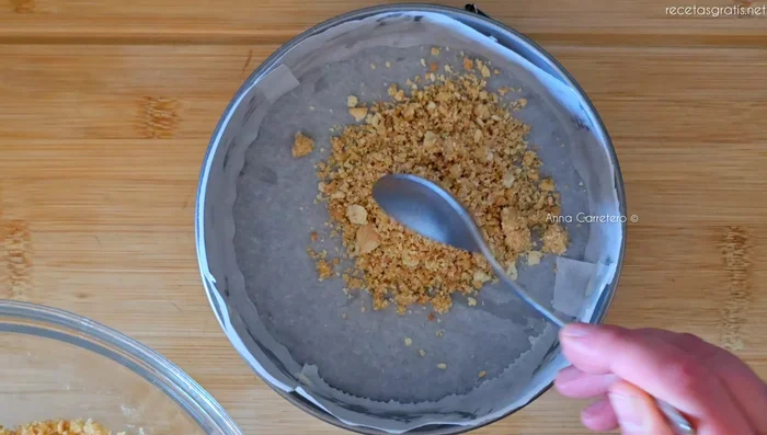 Vierte la mezcla de galletas en el molde y presiona con una cuchara o vaso para compactarla. Refrigera.