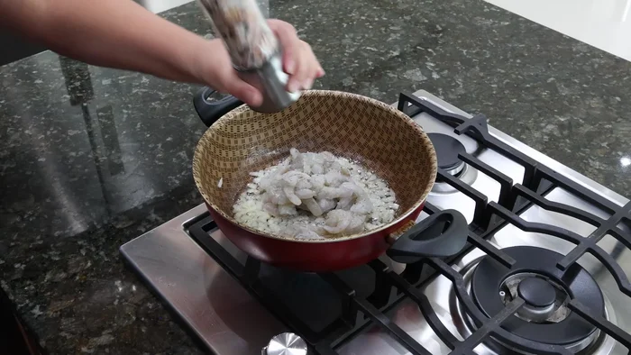 Agregar los camarones a la sartén y sazonarlos con sal, pimienta negra, ajo en polvo y pimentón.