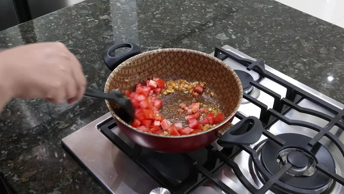 Agregar el jitomate picado a la sartén y cocinar hasta que esté guisado.