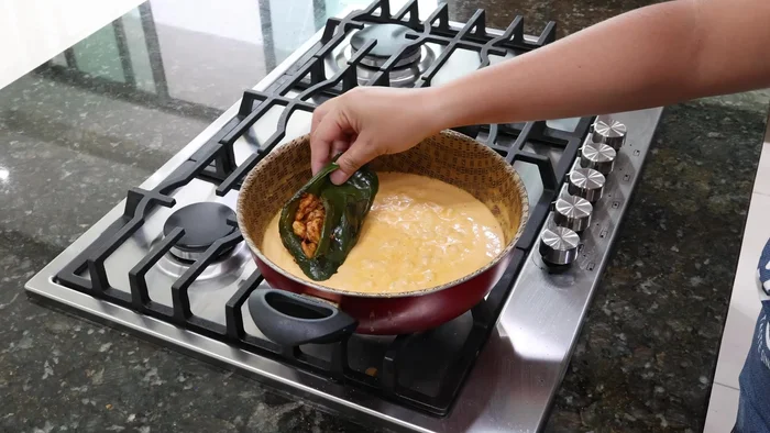 Colocar los chiles rellenos en la salsa y agregar queso rallado encima.