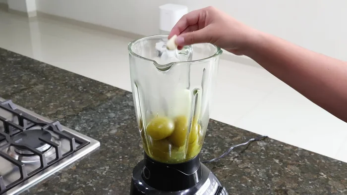 Licuar los tomatillos cocidos, una rodaja de cebolla, un diente de ajo, un puñado de cilantro fresco, una cucharadita de sal, orégano seco, una cucharadita de consomé de pollo (opcional) y media taza de agua.